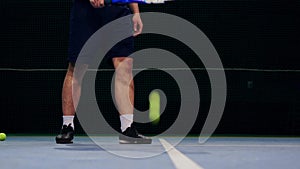 Tennis player holding the ball and getting ready to serve. Close-up feet tennis player preparing to serve. Knocking the