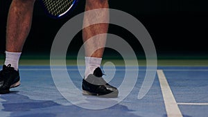 Tennis player holding the ball and getting ready to serve. Close-up feet tennis player preparing to serve. Knocking the