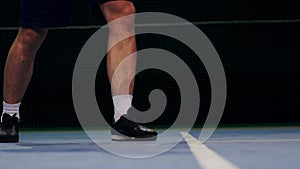 Tennis player holding the ball and getting ready to serve. Close-up feet tennis player preparing to serve. Knocking the