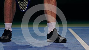 Tennis player holding the ball and getting ready to serve. Close-up feet tennis player preparing to serve. Knocking the