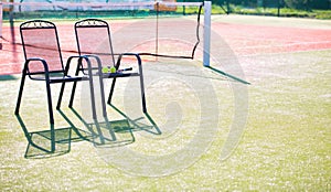 Tennis racket and ball on chair against court