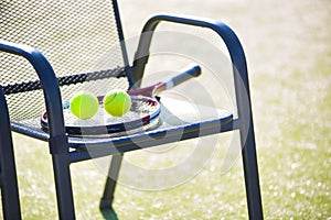 Tennis racket and ball on chair at court