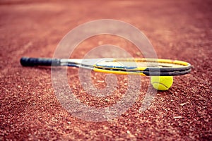 Tennis racket and ball on clay tennis court