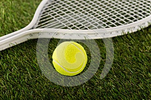 Tennis racket and ball on green grass