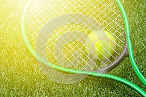 Tennis racket and ball on green grass