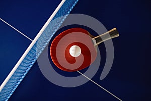 Tennis racket and ball on ping-pong table with net prepared for game