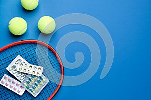 Tennis racket, balls and pills on blue background, flat lay with space for text. Doping concept