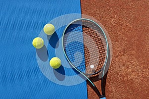 Tennis racket and balls on red clay court and blue gym mat. Concept of tennis active games. Sport background. Copy space