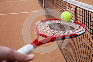 Tennis racket in hand and ball near black net on