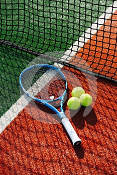 Tennis racket lying on the line between inner ond outer court next to the net