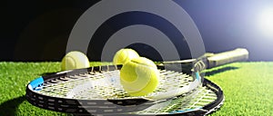 Tennis rackets and balls on green grass against dark background, space for text. Banner design