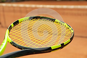 Tennis racquet against clay court close up