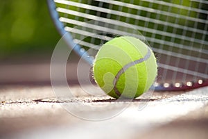 Tennis racquet and yellow tennis ball on outdoor court