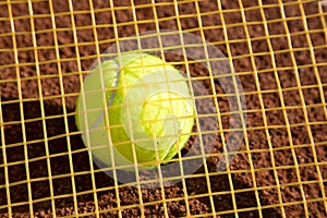 Tennis raquet with tennis ball on ash court