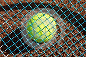 Tennis raquet with tennis ball on ash court