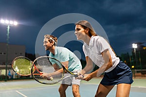 Tennis sport people concept. Mixed doubles player hitting tennis ball with partner standing near net