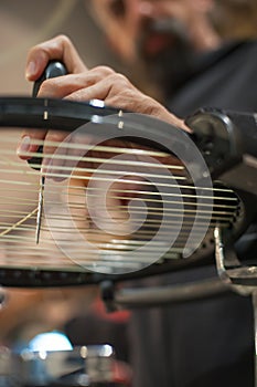 Tennis stringer holding awl and doing racket stringing