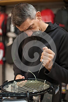 Tennis stringer holding awl and doing racket stringing