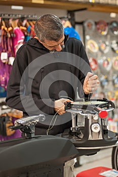 Tennis stringer holding awl and doing racket stringing