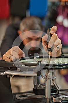 Tennis stringer holding awl and doing racket stringing