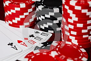 Tens Full of aces in a close-up macro image of a winning full house hand surrounded by stacks of Black and Red Poker betting chips