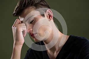 Tense androgynous man with hand on forehead