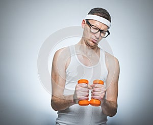 Tense funny man holding dumbbells