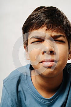 Tense indian boy with closed eyes over white background. close up