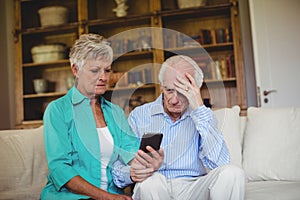 Tense senior couple looking at mobile phone