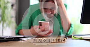 Tense and serious young business woman at office desk solves problem with smartphone