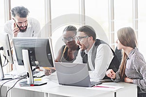 Tense work of four employees sitting in the front of monitors in the office room