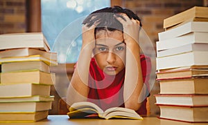 Tensed boy sitting with stack of books