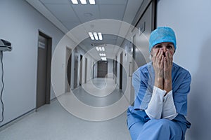 Tensed female surgeon covering her face in the hospital