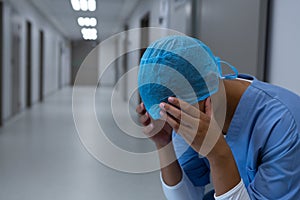 Tensed female surgeon sitting in the corridor of hospital