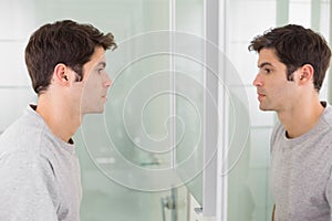 Tensed man looking at self in bathroom mirror