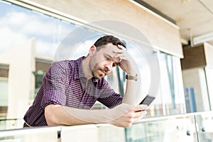 Tensed Man Reading Distressing News On Smartphone In Shopping Ma