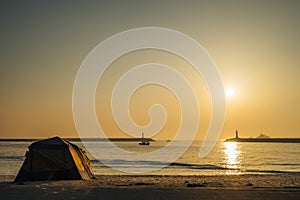 A tent on the beach near the sunrise sea.