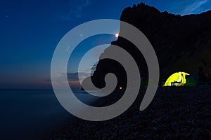 Tent on the beach at night. Full moon over the mountain