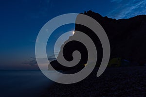 Tent on the beach at night. Full moon over the mountain