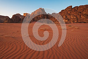 tent camp by the rocks on sunset in the red desert of Wadi Rum in Jordan with patterns on sand