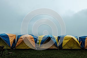 Tent in camping with flog and mountain view. Camping activities in rain-filled holiday. Tent on campsite by the hill in rainy day