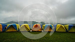 Tent in camping with flog and mountain view. Camping activities in rain-filled holiday. Tent on campsite by the hill in rainy day photo