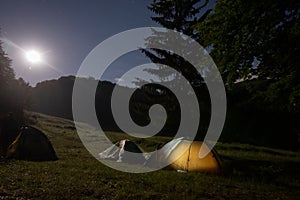 A tent glows under a night sky full of stars.