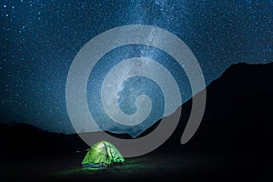 A tent glows under a night sky Milky May full of stars. Elbrus N