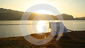 tent on lake coast at sunrise, orange color outdoor activity, camping and traveling