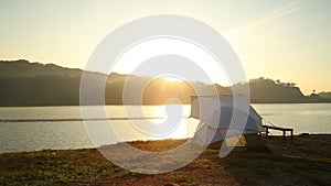 tent on lake coast at sunrise, orange color outdoor activity, camping and traveling