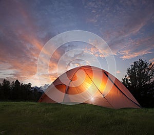 Tent with light inside at dusk near the Grand Teton mountains