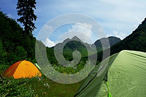 Tent in mountains with beautiful summer landscape