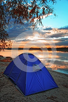 Tent by the river on the background of an autumn sunrise