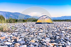 Tent on riverbed rock beach